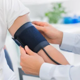 Manos colocando correctamente un brazalete de presión arterial en el brazo